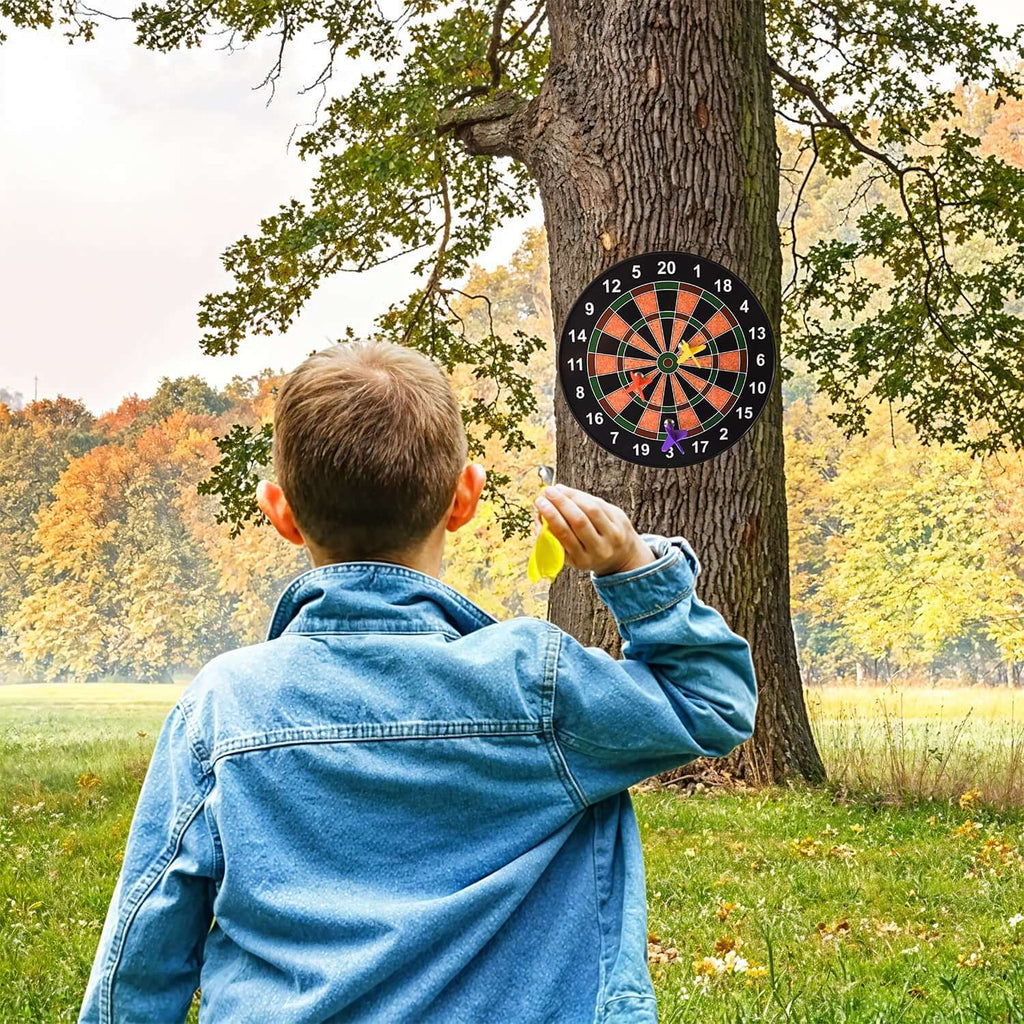 Child throwing a magnetic dart at a dartboard mounted on a tree in an outdoor setting, featuring the magnetic dartboard game set.