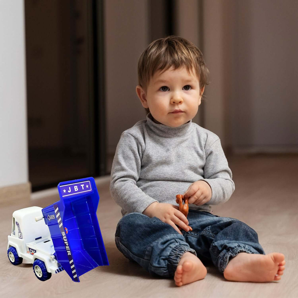 Child playing with a friction powered dumper truck for kids, engaging with the toy on the floor.