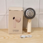 Rechargeable Lint Remover for Clothes placed next to its packaging and USB charging cable.