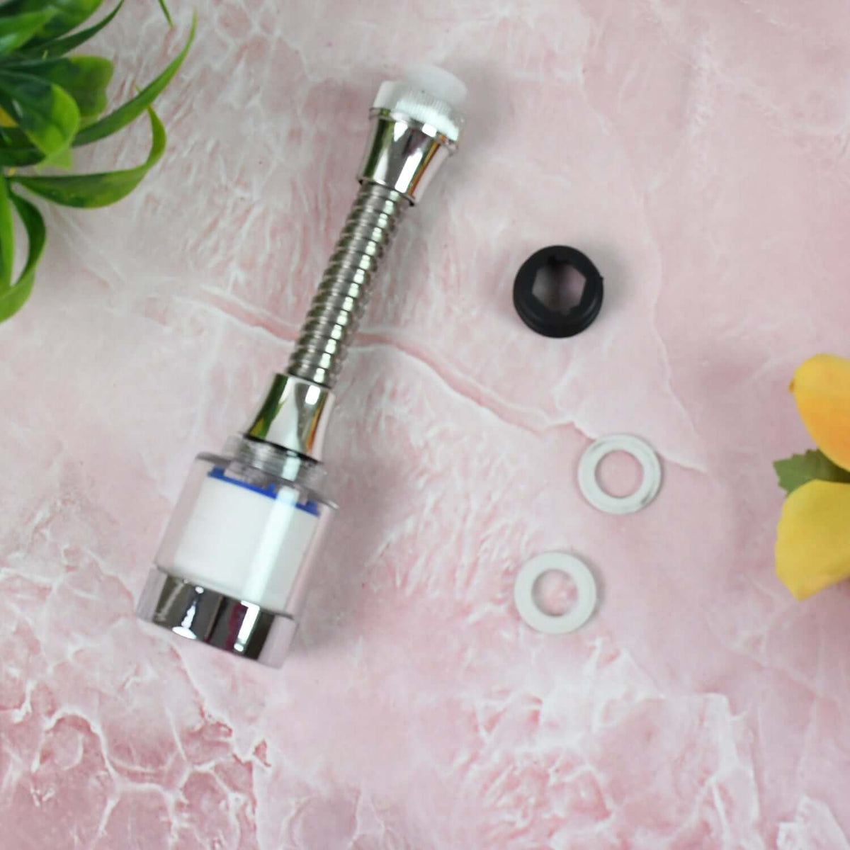 Water-saving faucet extender with 360 degree flexible neck and accessories on pink surface.