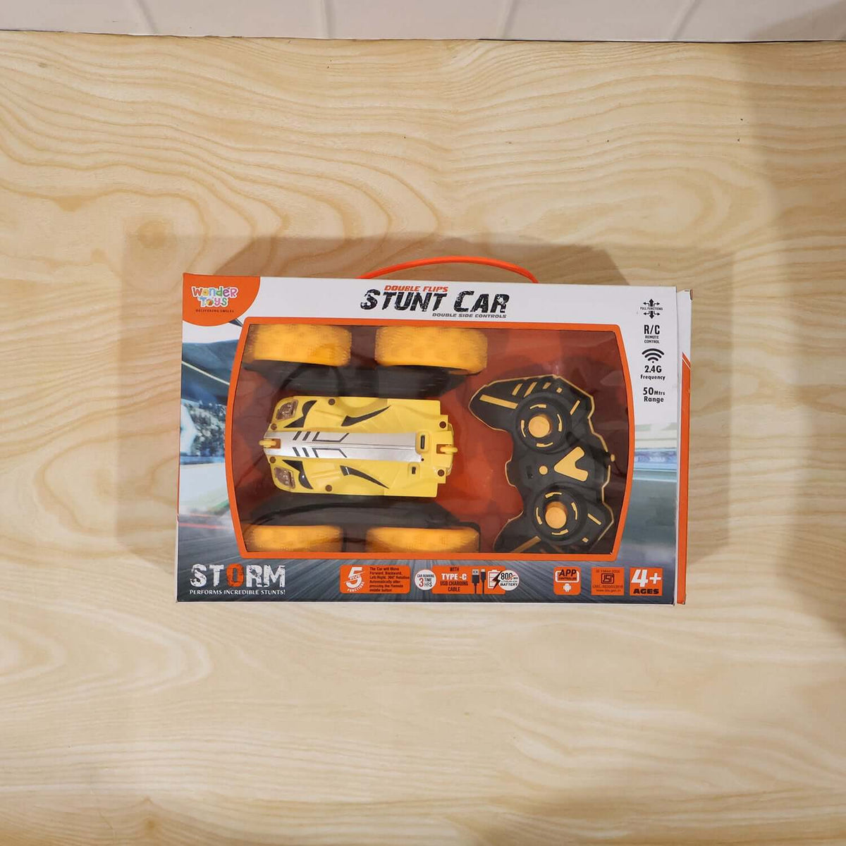 Remote Control Double Flip Stunt Car, Rechargeable in packaging on a wooden surface.