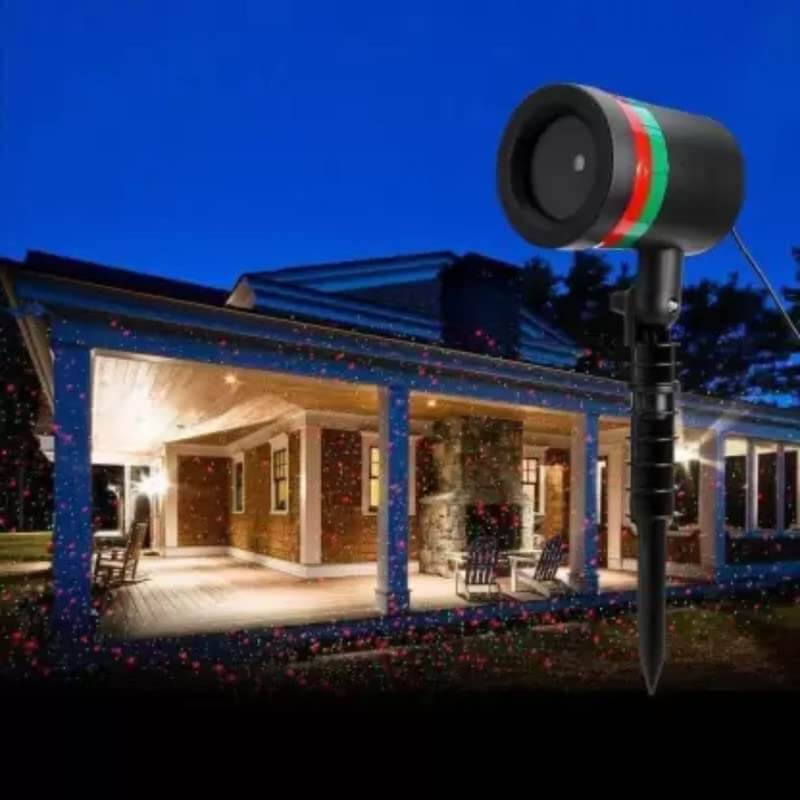 Star fairy laser light projector illuminating a porch with red and green moving dots against a twilight sky.