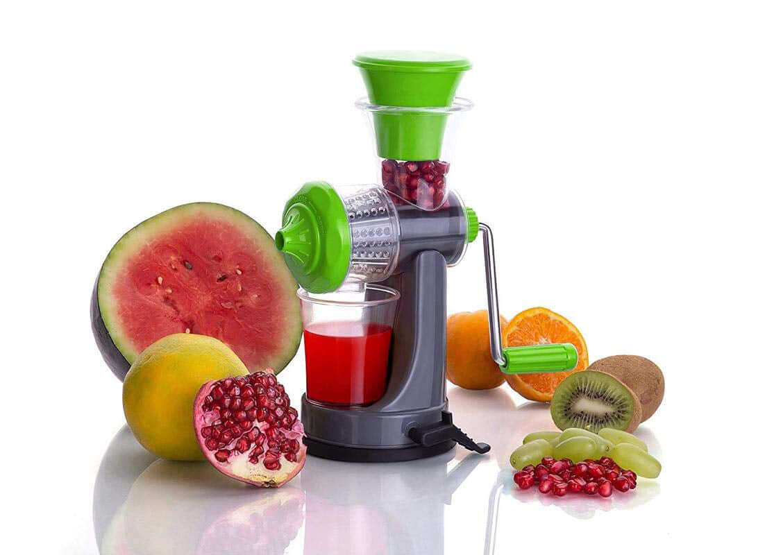 Manual fruit juicer without electricity displayed with fresh fruits and a glass of juice.
