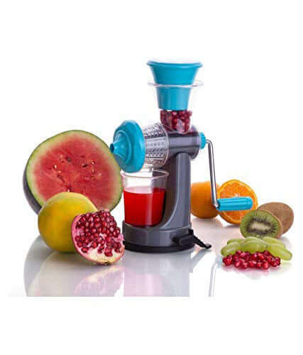 Manual fruit juicer without electricity with pomegranate juice and fresh fruits on a reflective surface.
