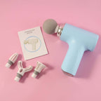 Electric Massage Gun with Interchangeable Heads, featuring multiple interchangeable heads and user manual on pink background.