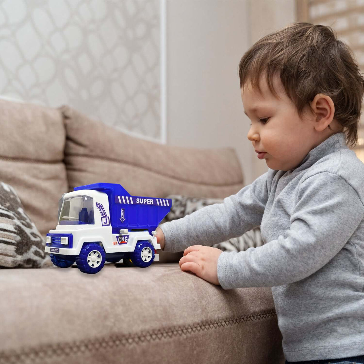 Big Friction-Powered Dumper Toy Truck for Kids being played with by a toddler on a couch.