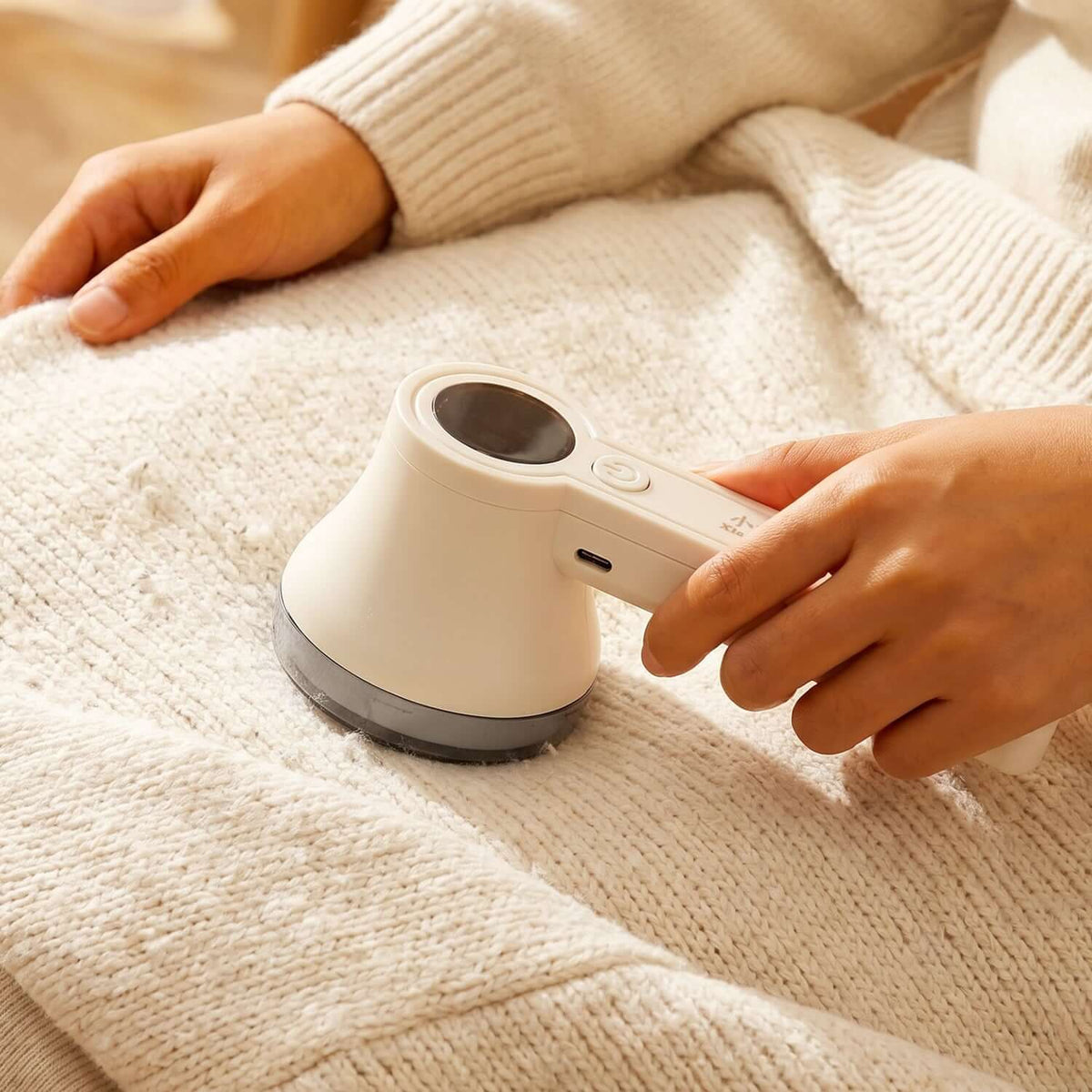 Rechargeable Lint Remover for Clothes being used on a knitted garment to remove lint and fuzz.