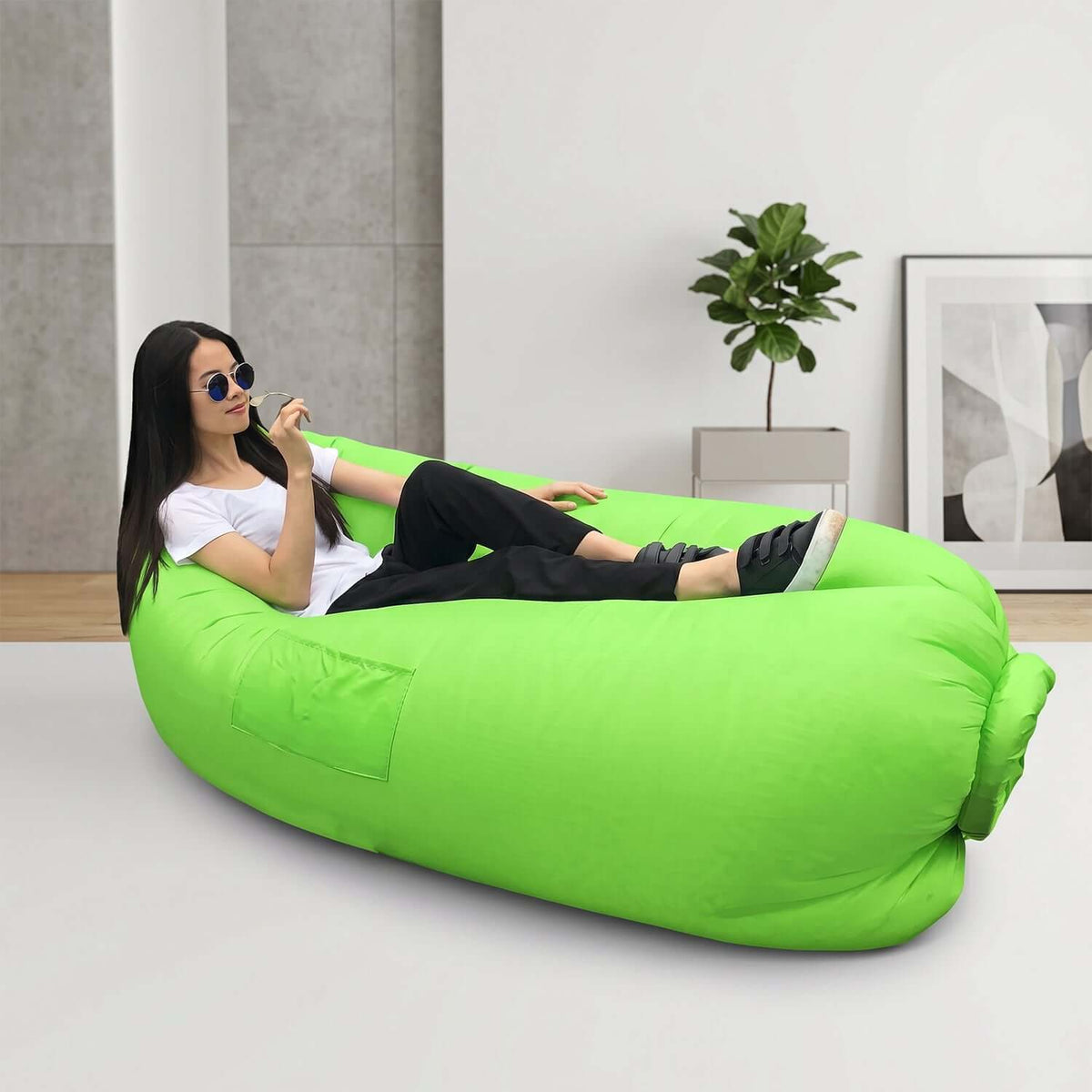 A woman relaxing on an inflatable air lounger for outdoor use in a bright green color.