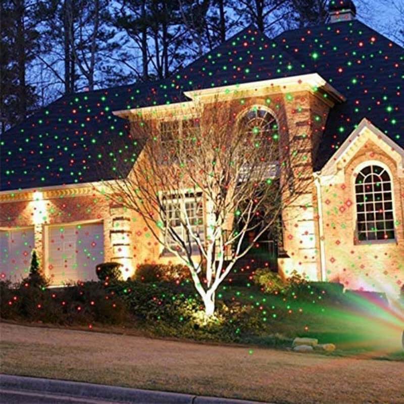 Star fairy laser light projector illuminating a home with moving red and green dots for festive decorations.