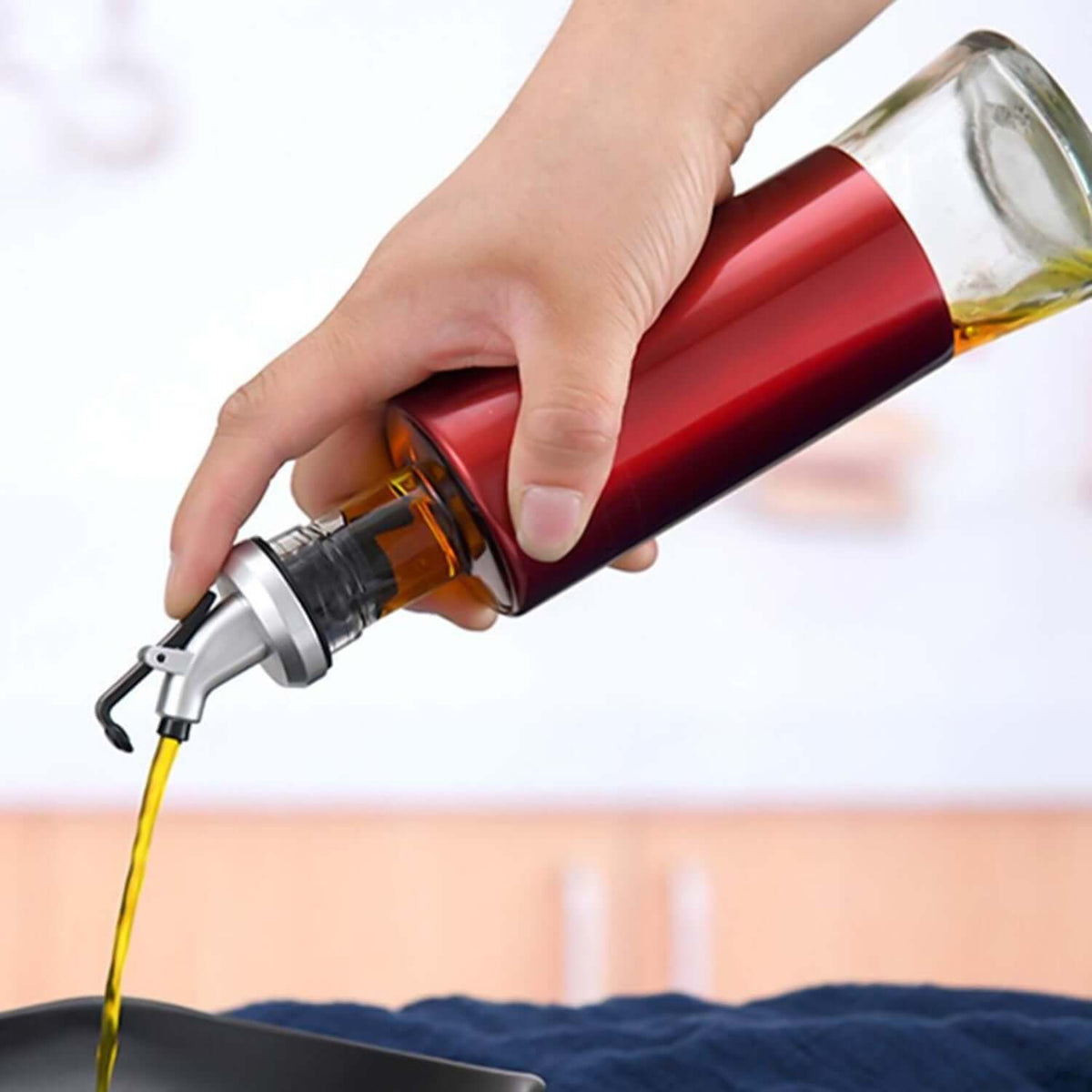 Glass oil vinegar dispenser bottle with golden pour spout in use for precise pouring.