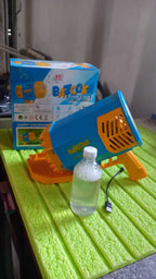 69-Hole Rechargeable Bubble Gun for Kids (Rocket Boom) with bottle and charging cable on a table.