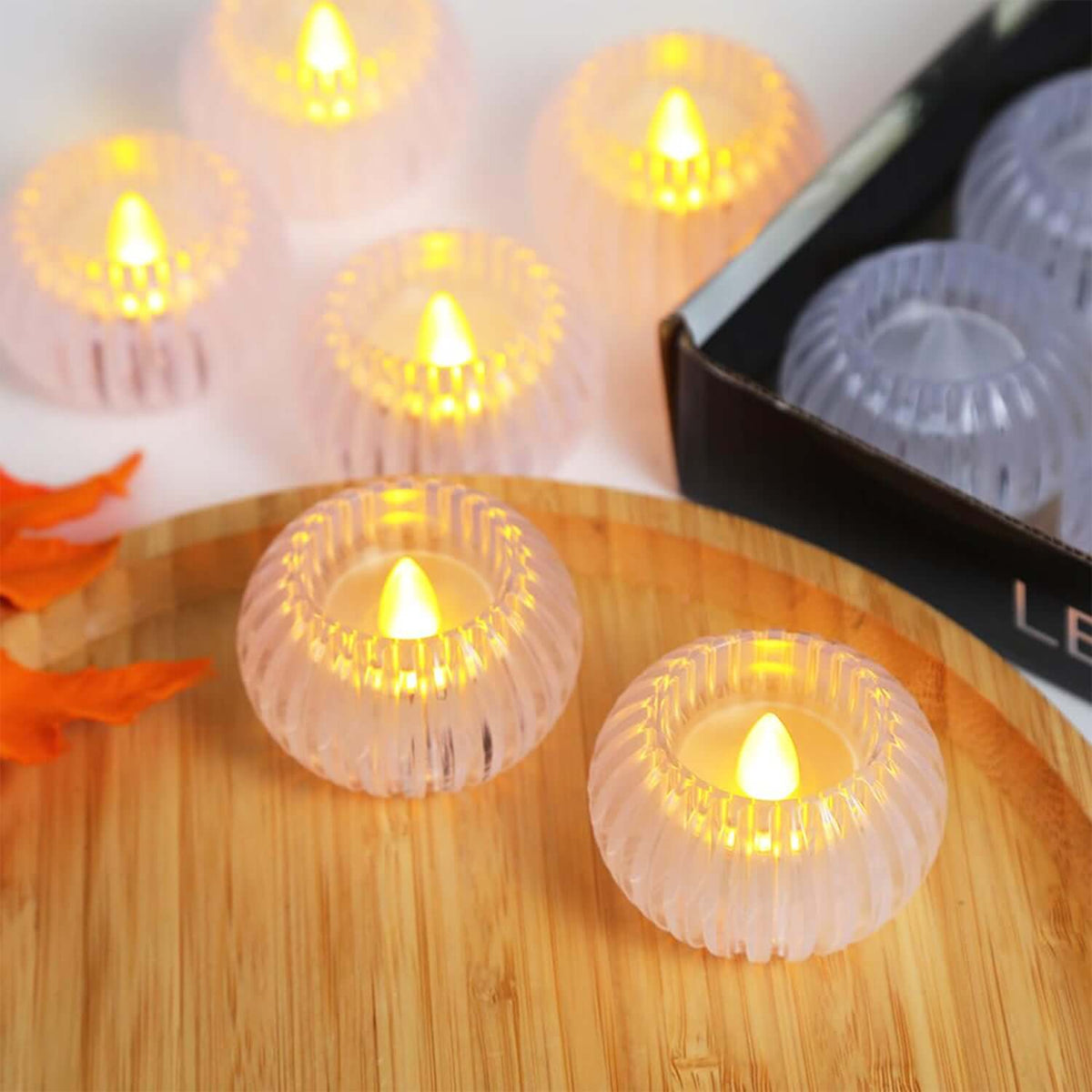 Set of 12 LED flameless tealight candles with flickering lights on a wooden surface.