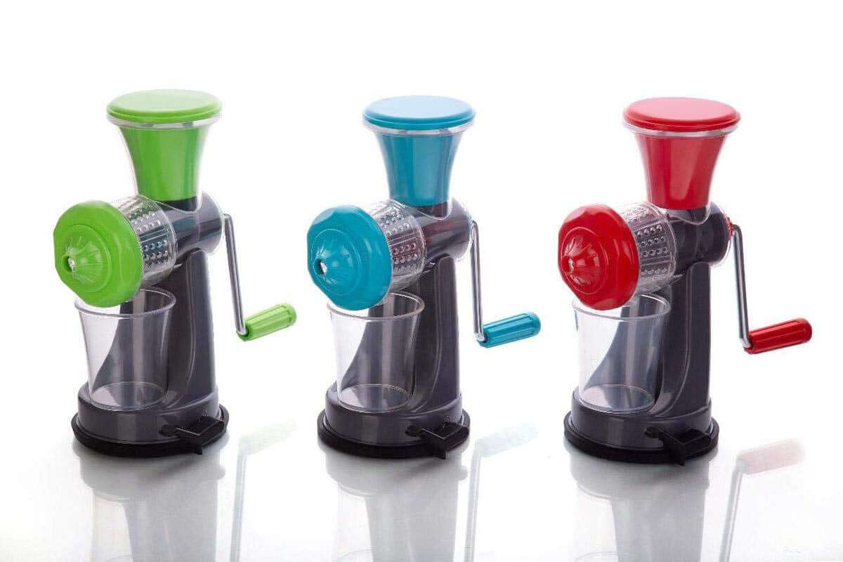 Manual fruit juicer without electricity in green, blue, and red colors on a reflective surface.