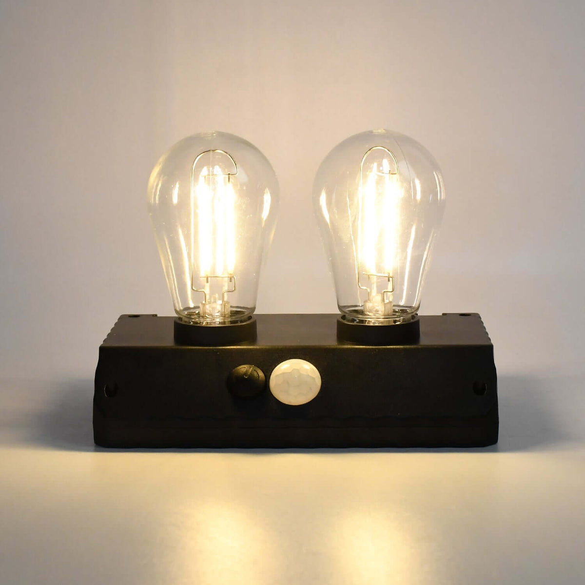Solar powered LED wall lamp featuring two illuminated bulbs, ideal for outdoor lighting.