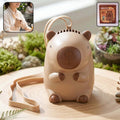 Cute bear neck fan with a neck strap placed on a wooden surface surrounded by greenery.